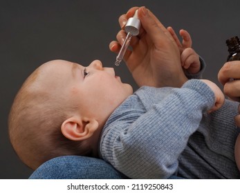 Parent Pipetting Cbd Oil Into Baby's Mouth. 
Mom Drips Medicine Vitamins With A Pipette To Infant