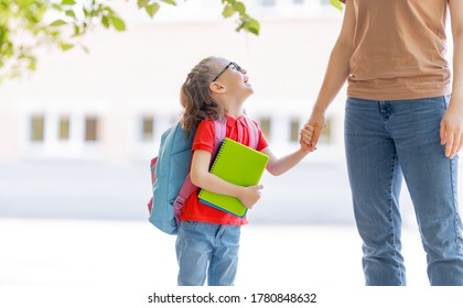 Parent and pupil of primary school go hand in hand. Woman and girl with backpack behind the back. Beginning of lessons. First day of fall. - Shutterstock ID 1780848632
