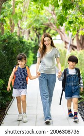 Parent And Pupil Of Primary School Go Hand In Hand. Woman And Kids With Backpack Behind The Back. Beginning Of Lessons.first Day At School.Mother Taking Daughter To School