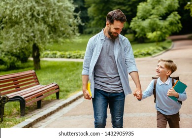 Parent take child to school. Pupil of primary school go study with backpack outdoors. Father and son go hand in hand. Beginning of lessons. Back to school. First day of fall. Elementary student.