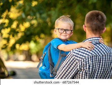 Parent Taking Child To School. Pupil Of Primary School Go Study. Father Holding Hand Of Little Son With Backpack Outdoors Beginning Of Lessons. Back To School. First Day Of Fall. Elementary Student.