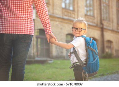 Parent Taking Child To School. Pupil Of Primary School Go Study With Backpack Outdoors. Father And Son Go Hand In Hand. Beginning Of Lessons. Back To School. First Day Of Fall. Elementary Student.