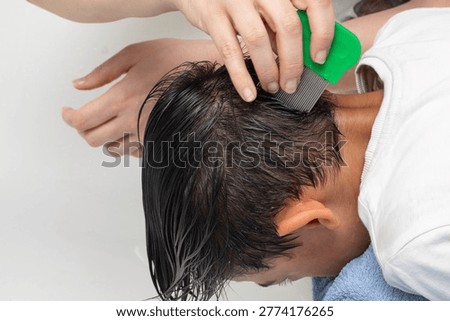 Parent using nit comb on child's wet hair to treat pediculosis infestation