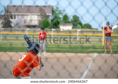 Parent view behind a chain link fence and home plate with a batter ready