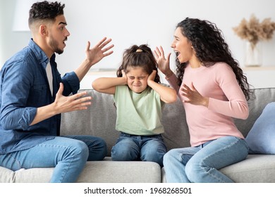 Parental Quarrels. Arab Man And Woman Arguing In Front Of Their Child, Upset Little Girl Covering Ears With Hands Not To Listen Conflict, Stressed Female Kid Sitting Between Shouting Parents - Powered by Shutterstock