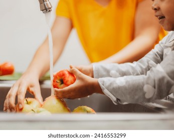 Parent-Child Bonding Activity: Teaching Healthy Habits Through Fruit Washing Under Running Water in the Kitchen - Powered by Shutterstock