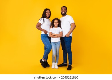 Parenthood And Childhood Concept. Full Body Length Of Smiling Young Black Parents Mom Dad Standing With Child Teen Girl, Daughter Posing With Folded Arms Isolated On Yellow Orange Background