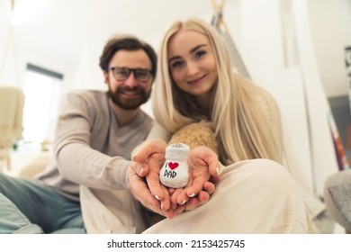 Parenthood concept. Young excited caucasian married couple holding a white baby shoe. Focus on the foreground. High quality photo