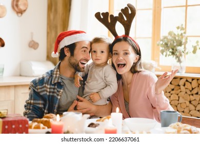 Parenthood concept. Young happy caucasian family of three taking selfie videocall looking at camera while celebrating Christmas New Year in Santa Claus red hats at home - Powered by Shutterstock