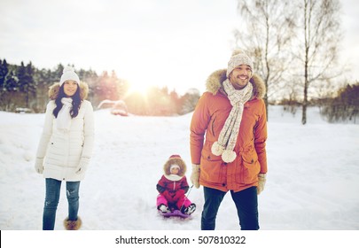 Parenthood, Fashion, Season And People Concept - Happy Family With Child On Sled Walking In Winter Outdoors