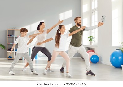 Parenthood and sport lifestyle. Happy active husband, wife and their two children doing family yoga session together. Family in comfortable clothes performs standing in same pose in bright home gym. - Powered by Shutterstock