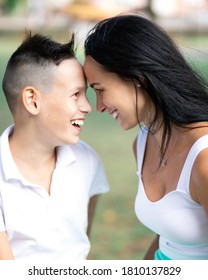 Parenting, Family And Single Parent Concept - A Happy Mother And Teen Son Smiling. Yung Mom And Teenage Son Look At Each Other And Laugh In Park.