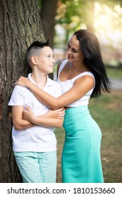 Parenting, Family And Single Parent Concept - A Happy Mother And Teen Son Smiling. Young Mom And Teenage Son Look At Each Other And Laugh In Park.