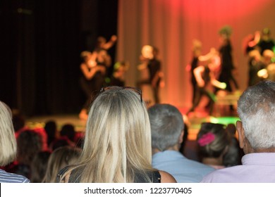 Parents In An Audience Hall Watching A Performance Of Children On A Stage Of A School Theater. Concept: Big Event On An Open Day At School.