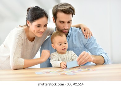 Parents with baby girl playing cards - Shutterstock ID 338701514