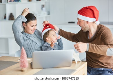 Parents Being Silly With Kid And Santa Hat On Laptop Computer At Home