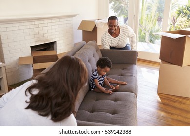 Parents Carry Son On Sofa Into New Home On Moving Day - Powered by Shutterstock