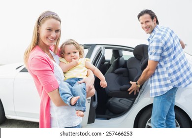 Parents Carrying Baby And Her Car Seat Out Of The Car