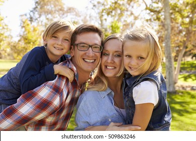 Parents carrying their two young kids in park look to camera - Shutterstock ID 509863246