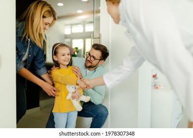 Parents And Child Girl In Meeting With Doctor Orthodontist, Dental Examination And Dentist Consultation. The Girl Is Holding Her Favorite Bear.