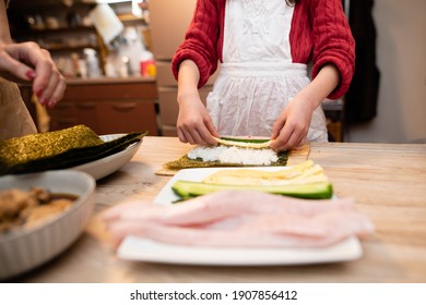 Parents And Child Making Sushi Rolls