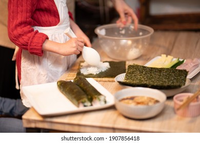 Parents And Child Making Sushi Rolls