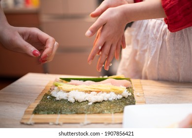 Parents And Child Making Sushi Rolls