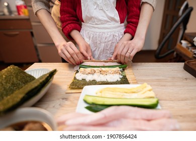 Parents And Child Making Sushi Rolls