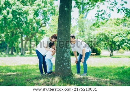 Parents and child playing hide-and-seek in the woods