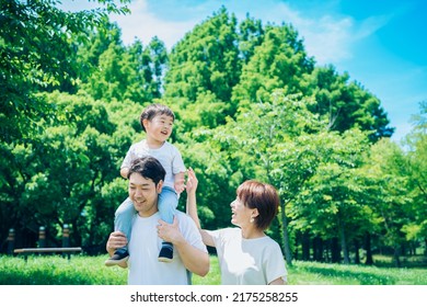 Parents and child playing while piggybacking in the park - Shutterstock ID 2175258255
