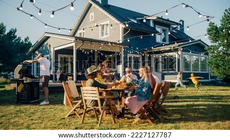 Parents, Children and Friends Gathered at a Barbecue Dinner Table Outside a Beautiful Home. Multicultural Old and Young People Have Fun, Eat and Drink. Garden Party Celebration in a Backyard.