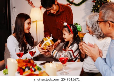 Parents, children, and grandparents gather at home for a joyful Christmas and New Year celebration, also marking the granddaughter’s birthday. They share wine, food, drinks, and exchange gift boxes - Powered by Shutterstock