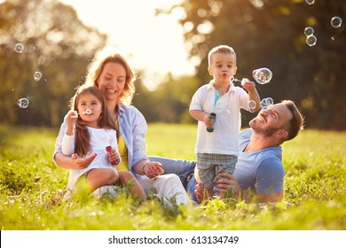 Parents with children having fun in nature with soap bubbles - Shutterstock ID 613134749