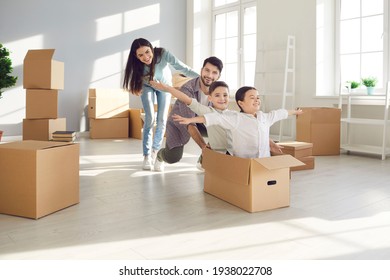 Parents and children moving in. Husband and wife with their children, who are sitting in a cardboard box having fun in their new home. Concept of buying your own home and moving.