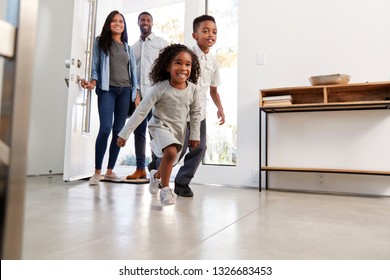 Parents And Children Returning Home Opening Front Door And Running Inside