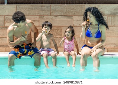 Parents and children sit by the pool, enjoying colorful popsicles and dipping their feet in the water. They relax and savor a sunny, fun-filled summer day. - Powered by Shutterstock