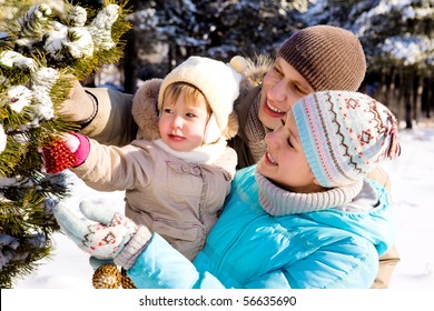 Parents And Daughter Decorating Christmas Tree In A Winter Park