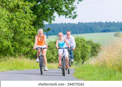 Parents and daughter have bicycle or bike tour on country lane