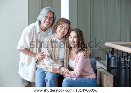 Parents and daughters happily embrace each other in the living room while taking pictures together within the family.