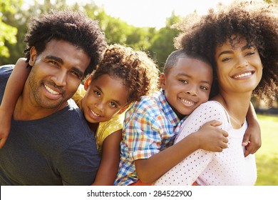 Parents Giving Children Piggyback Ride In Garden - Powered by Shutterstock