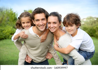 Parents giving piggyback ride to children - Powered by Shutterstock