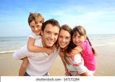 Parents giving piggyback ride to kids at the beach