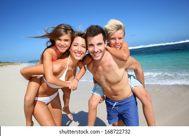Parents giving piggyback ride to kids at the beach