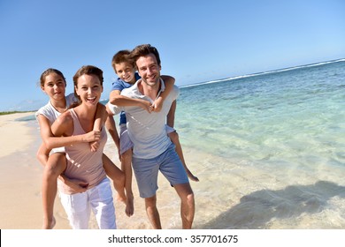 Parents giving piggyback ride to kids on a sandy beach