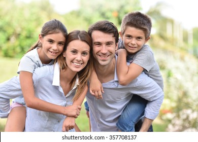 Parents Giving Piggyback Ride To Kids Outside