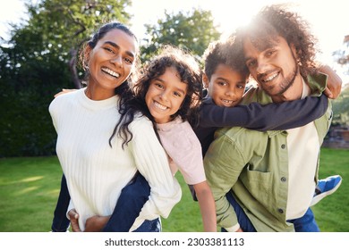 Parents giving their kids piggybacks, waist up, close up smiling at camera - Powered by Shutterstock