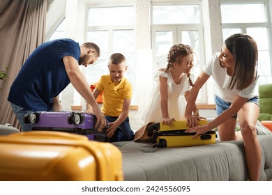 Parents help their children to packing clothes in living room at home before leaving for children's health camp. Joyful mood before trip. Concept of tourism, holiday, vacation, relaxation. Ad - Powered by Shutterstock