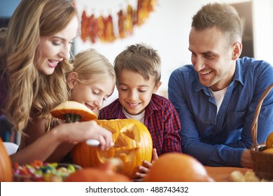 Parents helping children in carving pumpkins
