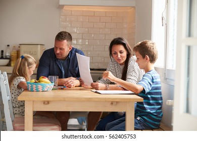 Parents Helping Children With Homework At Kitchen Table - Powered by Shutterstock