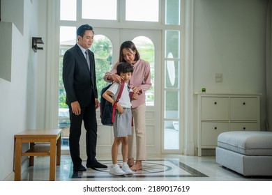 Parents helping son in uniform to get ready to leave home for school. - Shutterstock ID 2189017619